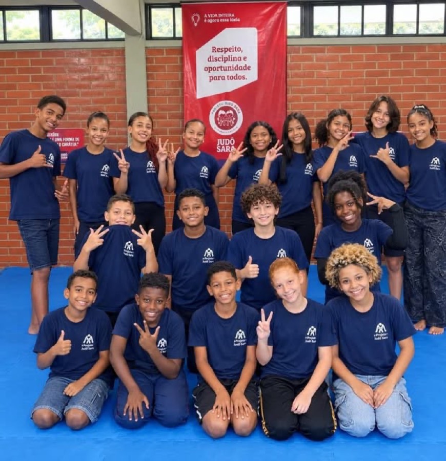 Turma de alunos do Projeto Judô Sara com camisetas do projeto sobre o tatame